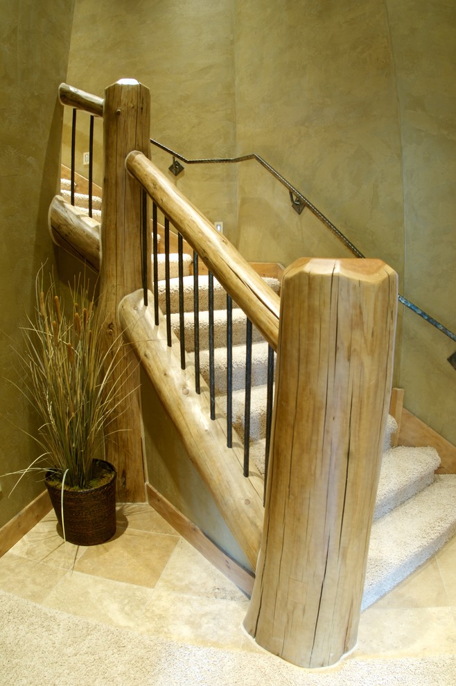 На фото: изогнутая деревянная лестница в стиле рустика с ступенями с ковровым покрытием и деревянными перилами