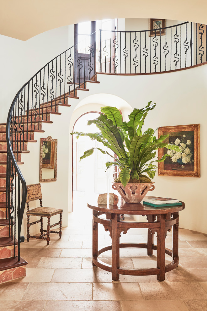 Inspiration for an expansive mediterranean curved metal railing staircase in Los Angeles with limestone treads and terracotta risers.
