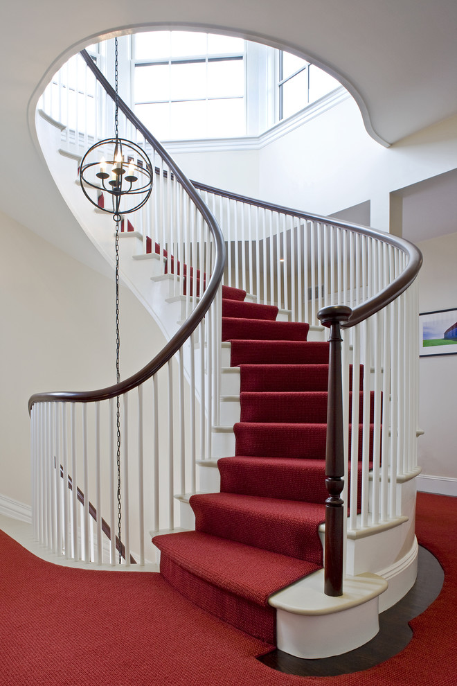 Example of a classic marble curved wood railing staircase design in Denver with painted risers