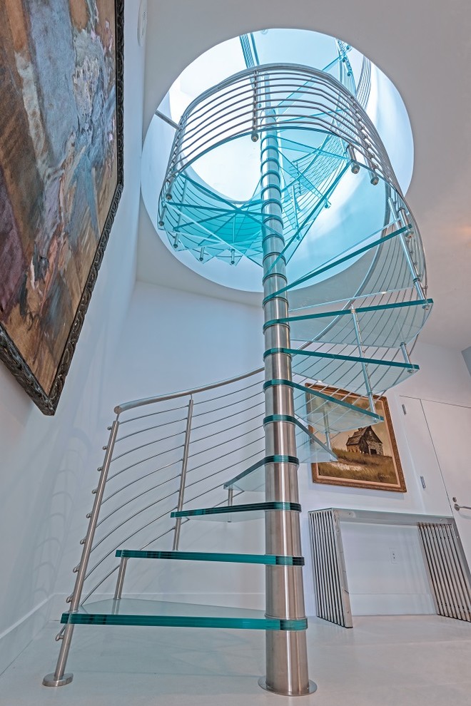 Aménagement d'un escalier hélicoïdal moderne avec des marches en verre et un garde-corps en métal.