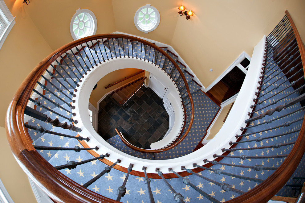 Classic carpeted spiral staircase in New York with wood risers.