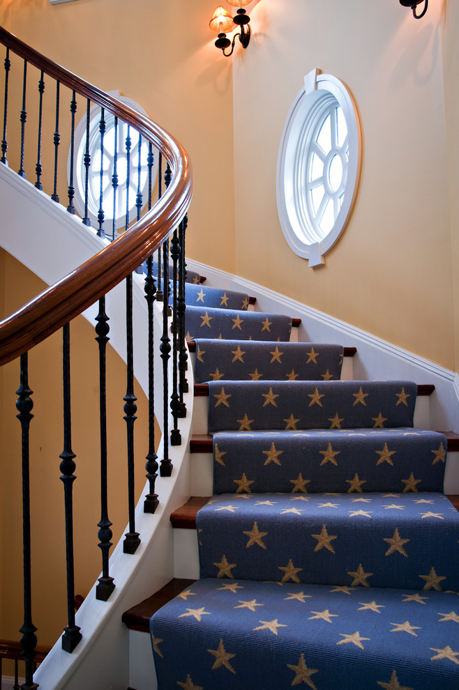 На фото: винтовая деревянная лестница в классическом стиле с ступенями с ковровым покрытием с