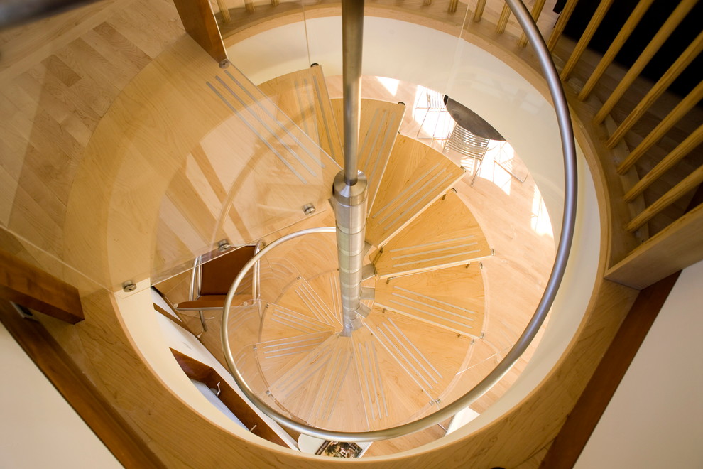 Ejemplo de escalera de caracol moderna pequeña sin contrahuella con escalones de madera y barandilla de vidrio