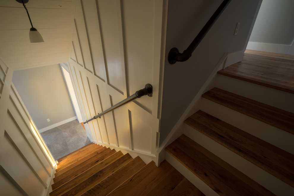 Ejemplo de escalera en L campestre grande con escalones de madera, contrahuellas de madera pintada y barandilla de metal