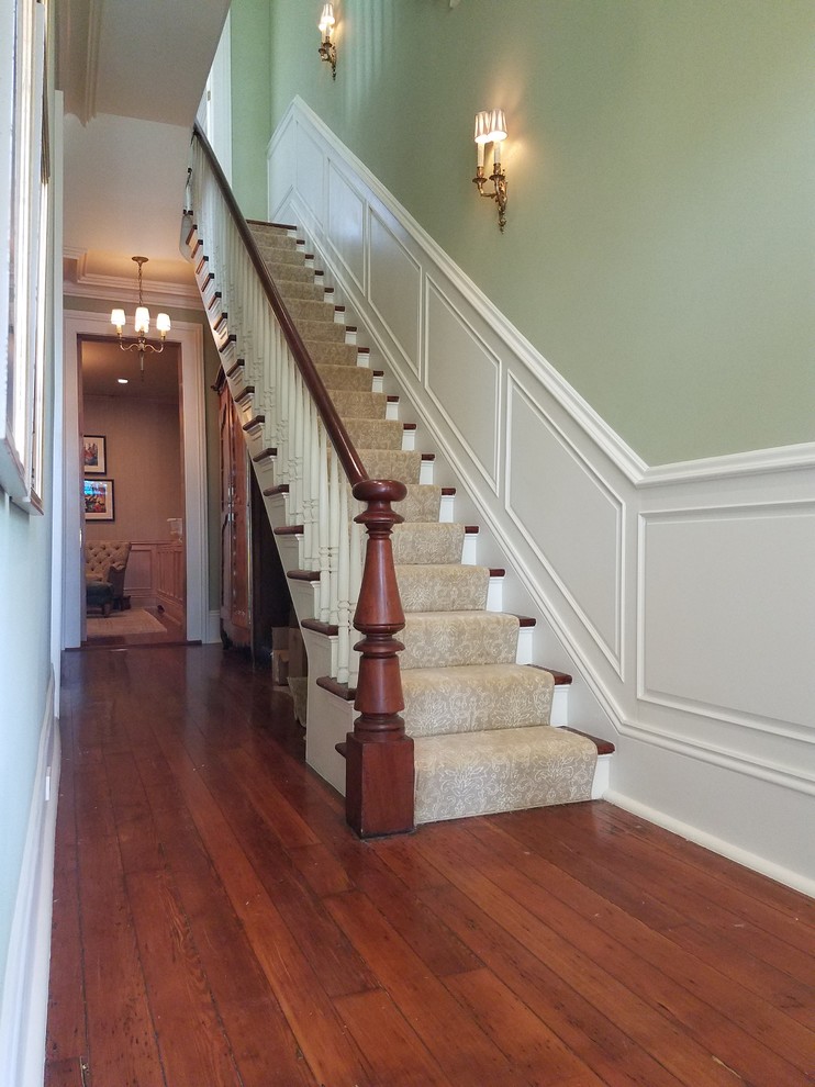 Diseño de escalera recta grande con escalones de madera, contrahuellas de madera pintada y barandilla de madera