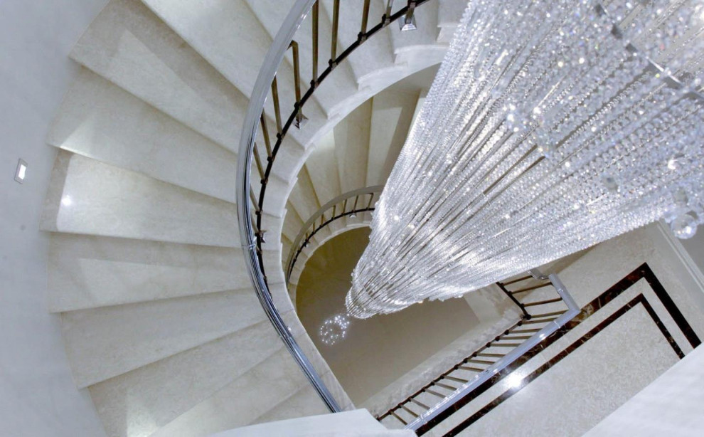 Bild på en stor funkis svängd trappa i marmor, med öppna sättsteg och räcke i metall