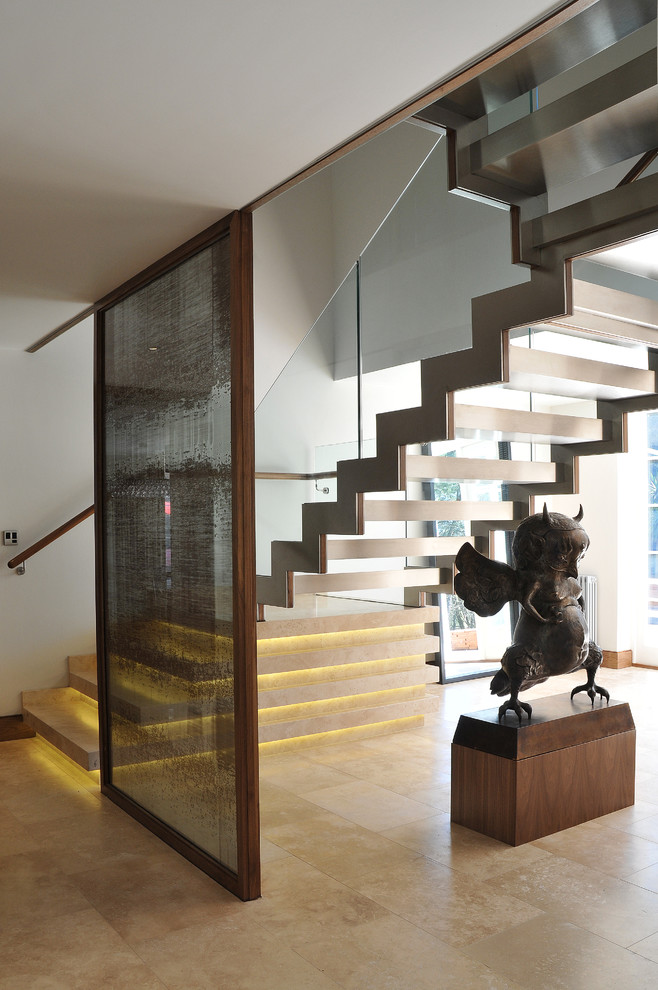Photo of a medium sized contemporary floating glass railing staircase in London with open risers and travertine treads.