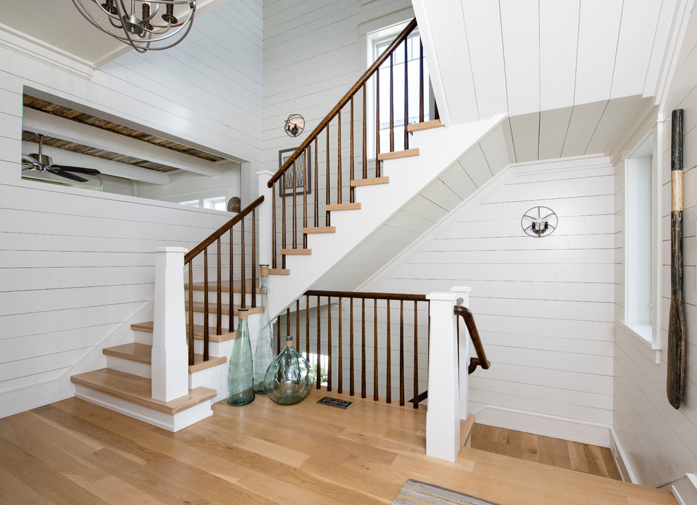 Diseño de escalera en U marinera con escalones de madera, contrahuellas de madera pintada y barandilla de madera