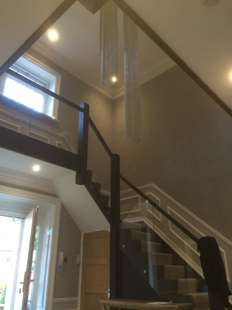 Photo of a large modern carpeted l-shaped wood railing staircase in Essex with carpeted risers.