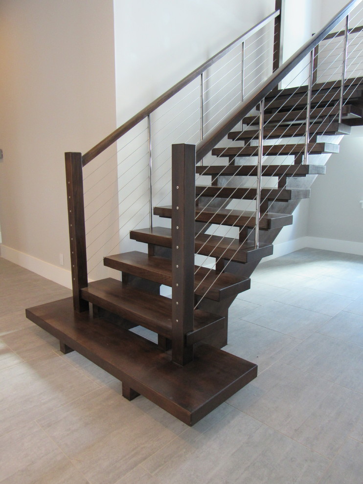 Foto de escalera suspendida actual sin contrahuella con escalones de madera y barandilla de cable