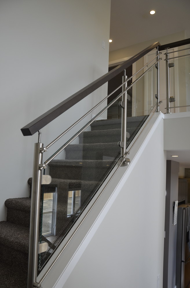 Small trendy carpeted u-shaped glass railing staircase photo in Other with carpeted risers
