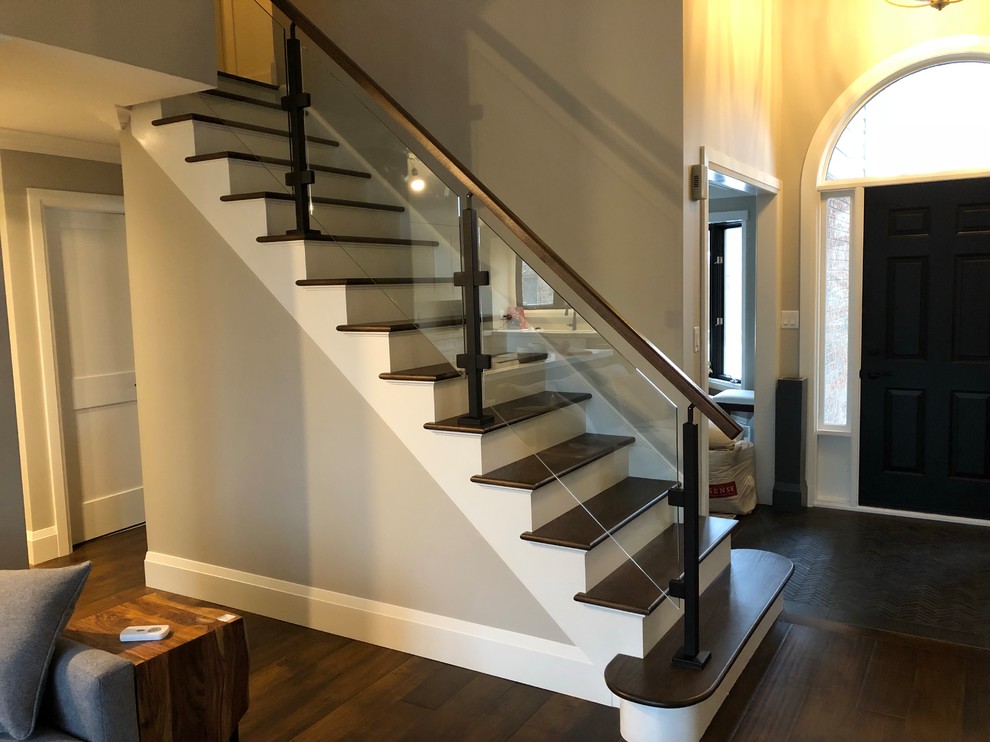 Contemporary wood straight glass railing staircase in Toronto with painted wood risers.