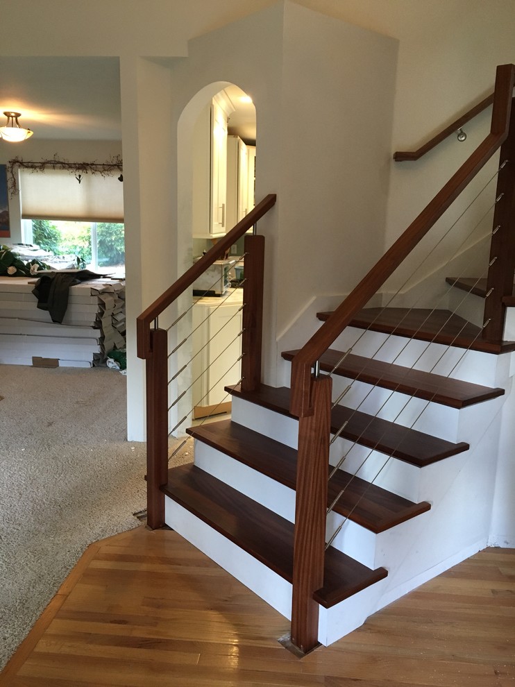 Diseño de escalera en L actual de tamaño medio con escalones de madera, contrahuellas de madera pintada y barandilla de varios materiales