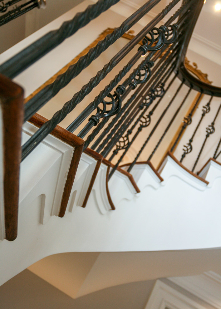 Ejemplo de escalera curva tradicional grande con escalones de madera, contrahuellas de madera y barandilla de metal