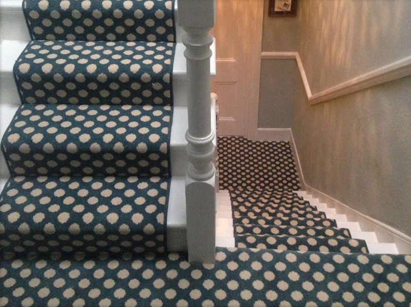 Photo of a carpeted u-shaped wood railing staircase in London with carpeted risers.