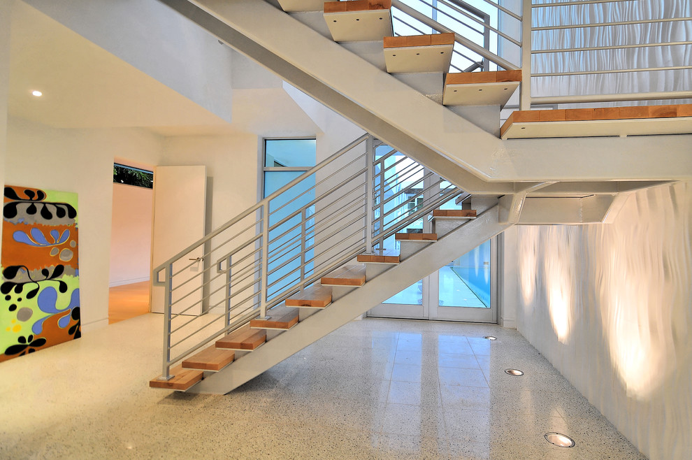 На фото: большая лестница на больцах в стиле модернизм с деревянными ступенями и металлическими перилами без подступенок