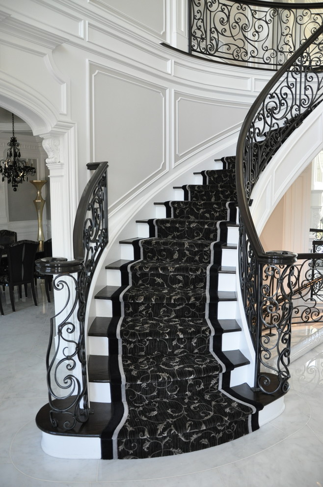 Стильный дизайн: большая изогнутая лестница в стиле неоклассика (современная классика) с деревянными ступенями и крашенными деревянными подступенками - последний тренд