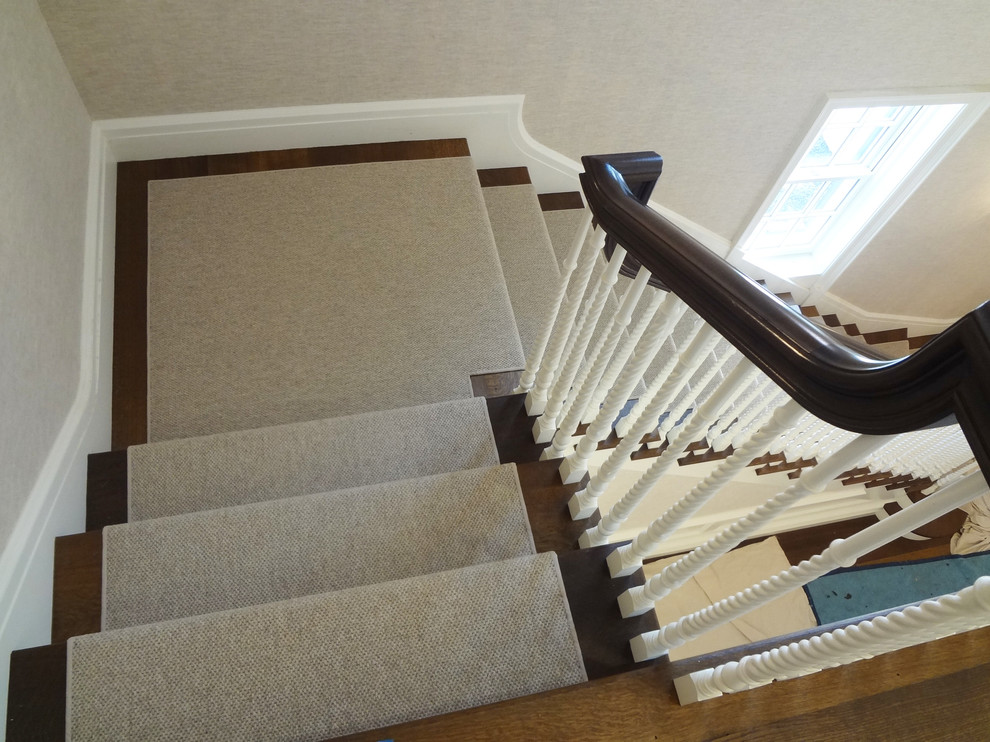 Cette image montre un grand escalier traditionnel en L avec des marches en moquette et des contremarches en moquette.