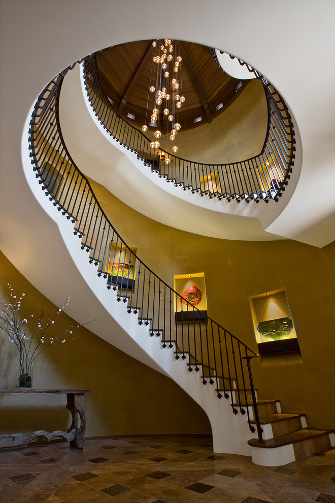 На фото: изогнутая лестница в средиземноморском стиле с деревянными ступенями с