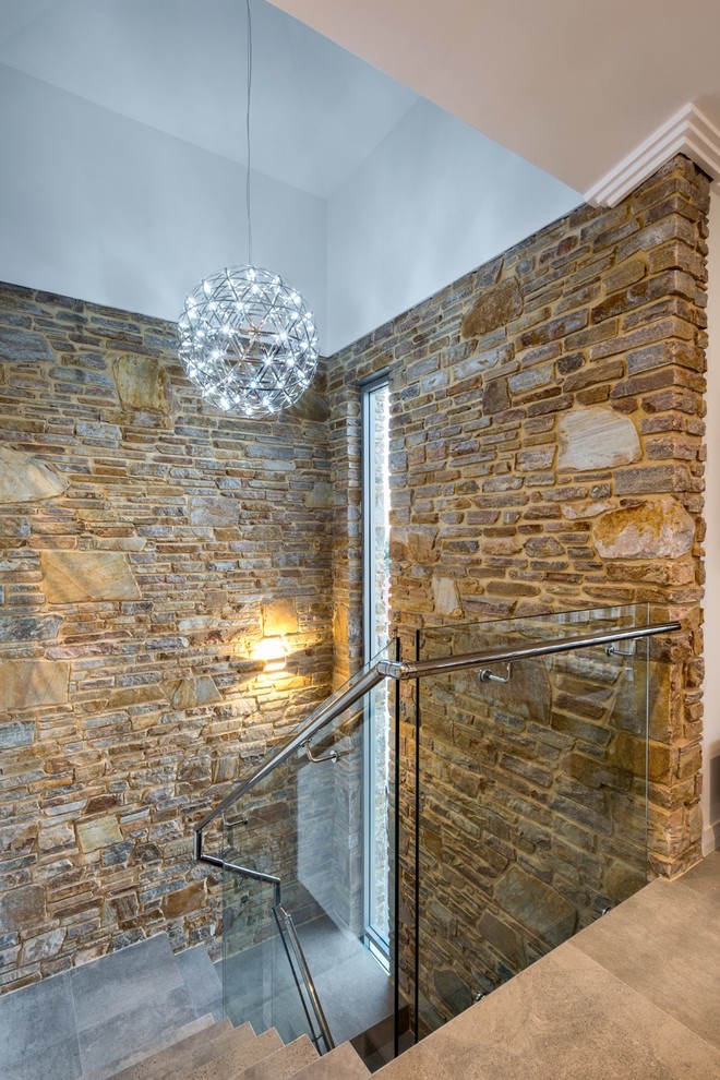 Bild på en mellanstor funkis u-trappa, med klinker, sättsteg i betong och räcke i glas