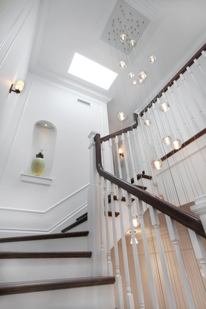 Пример оригинального дизайна: огромная п-образная лестница в классическом стиле с деревянными ступенями и крашенными деревянными подступенками