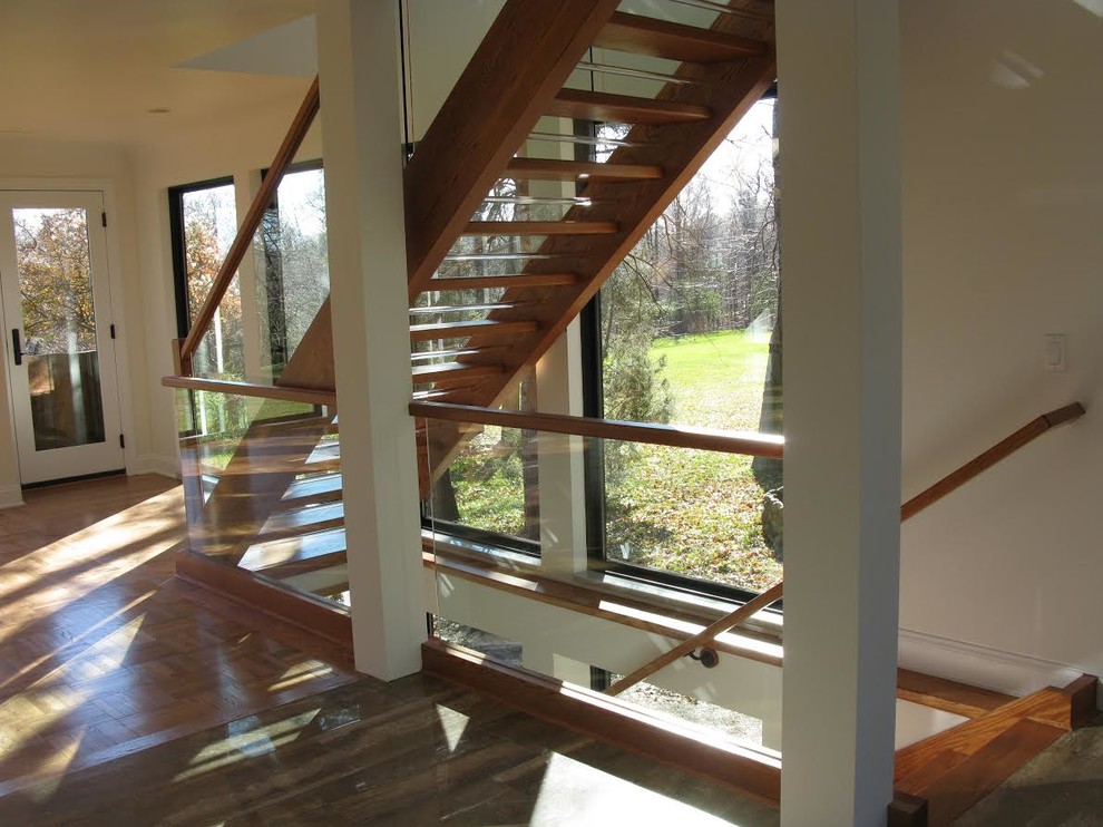 Modelo de escalera suspendida actual grande sin contrahuella con escalones de madera y barandilla de vidrio