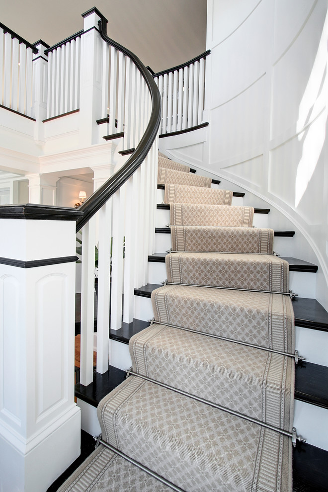 Idée de décoration pour un grand escalier peint courbe marin avec des marches en bois.