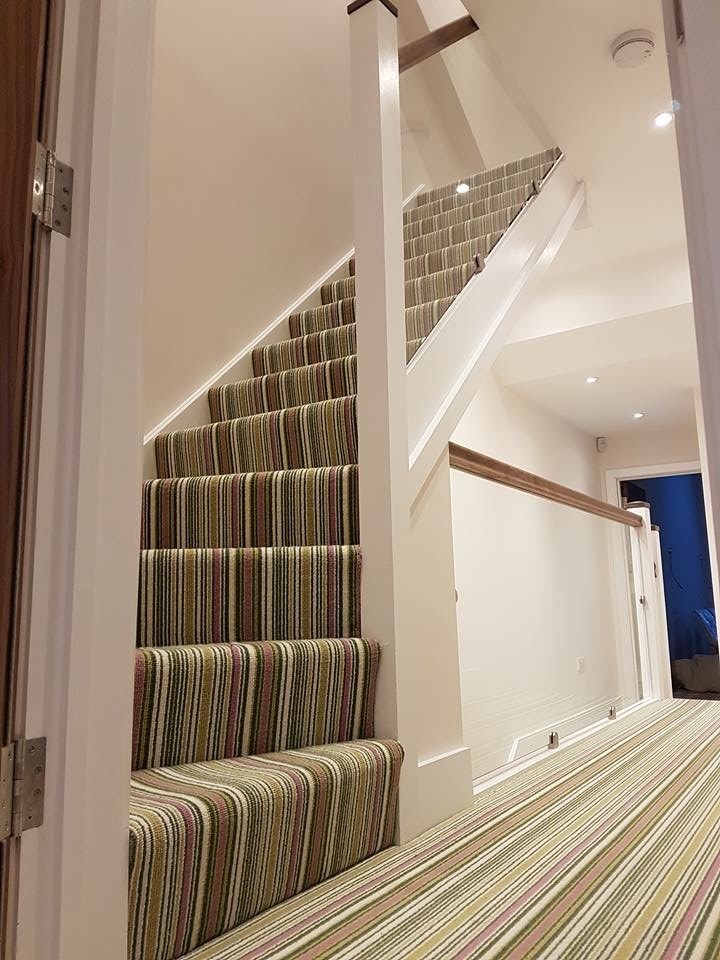 На фото: большая угловая лестница в стиле модернизм с ступенями с ковровым покрытием, ковровыми подступенками и деревянными перилами с