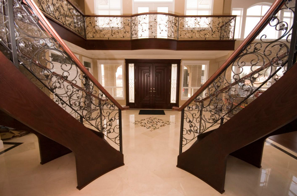 Inspiration pour un très grand escalier sans contremarche courbe traditionnel avec un garde-corps en matériaux mixtes et des marches en bois.