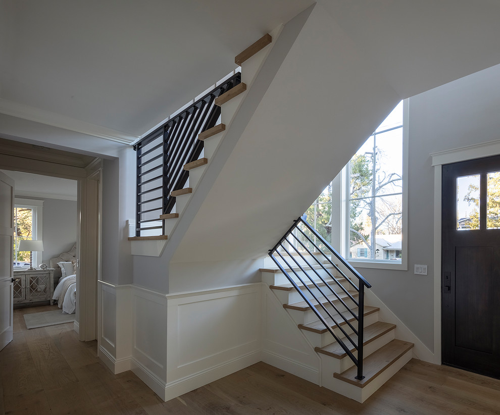 Diseño de escalera en U de estilo de casa de campo pequeña con escalones de madera, contrahuellas de madera y barandilla de metal