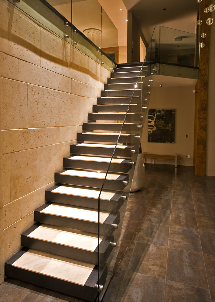 На фото: лестница на больцах в современном стиле с стеклянными перилами без подступенок с