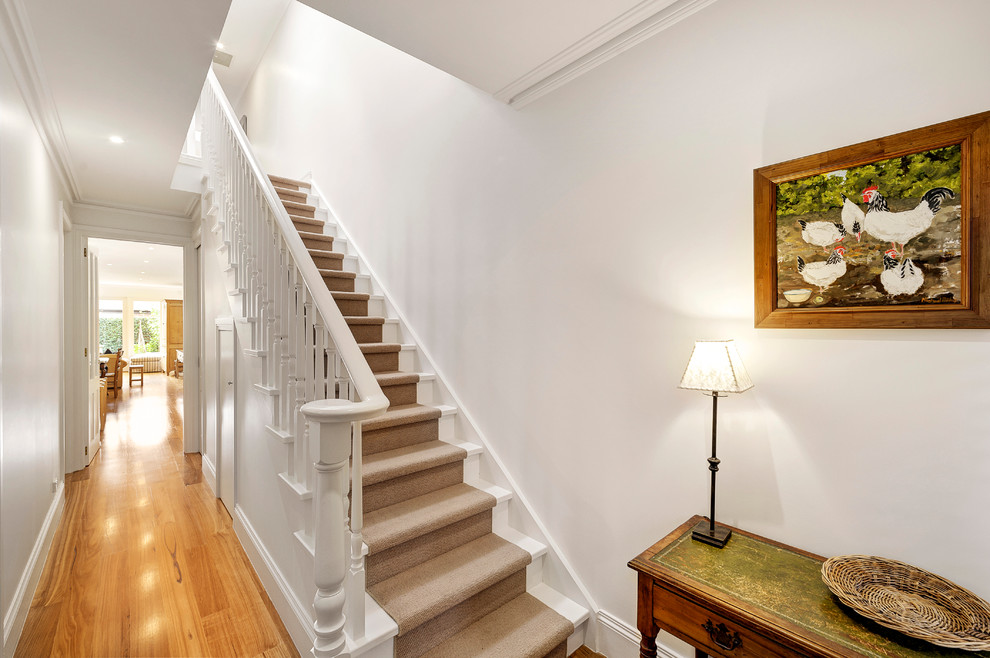 Diseño de escalera recta clásica de tamaño medio con escalones enmoquetados y contrahuellas de madera pintada
