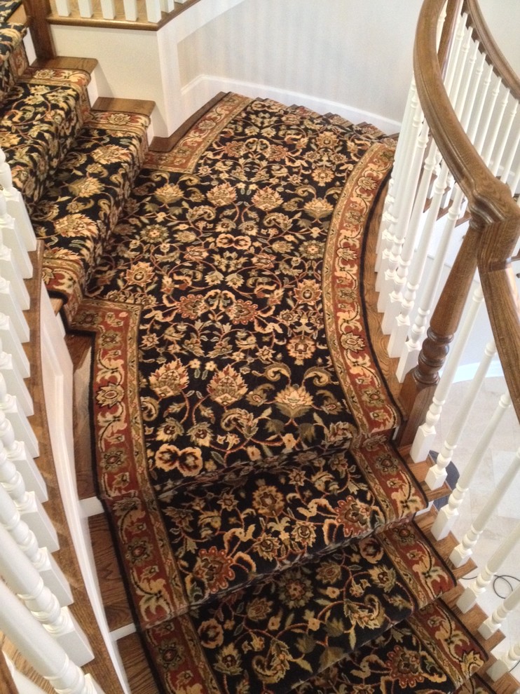 Пример оригинального дизайна: огромная изогнутая лестница в классическом стиле с ступенями с ковровым покрытием