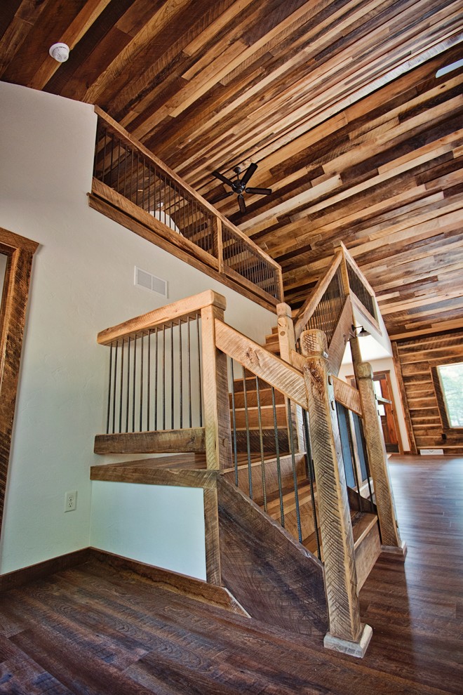 Imagen de escalera en L rural grande con escalones de madera, contrahuellas de metal y barandilla de madera