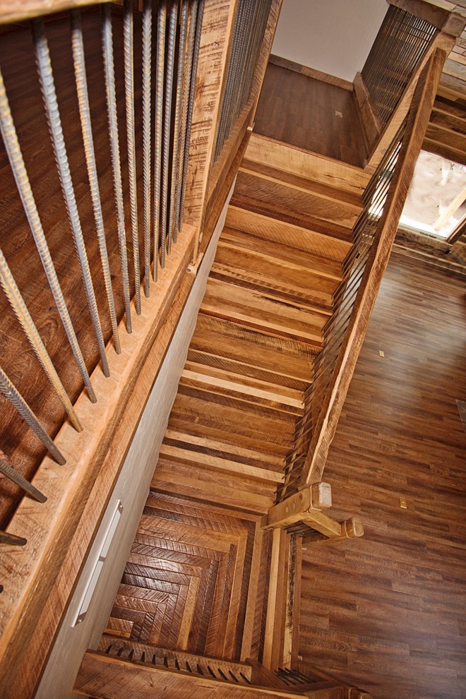Foto de escalera en L rústica grande con escalones de madera, contrahuellas de metal y barandilla de madera