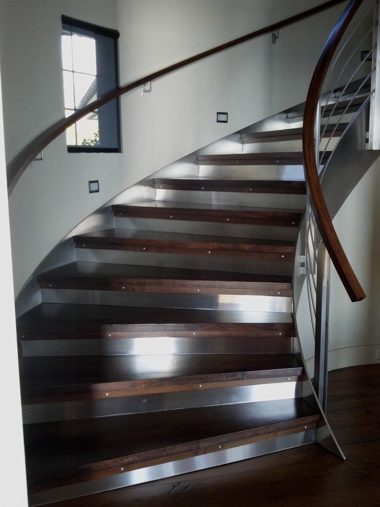 Свежая идея для дизайна: изогнутая металлическая лестница среднего размера в современном стиле с деревянными ступенями - отличное фото интерьера