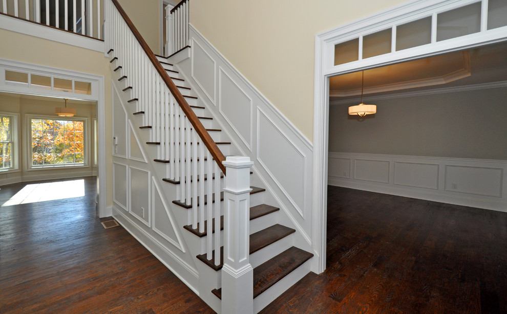 Aménagement d'un grand escalier peint droit classique avec des marches en bois et un garde-corps en bois.