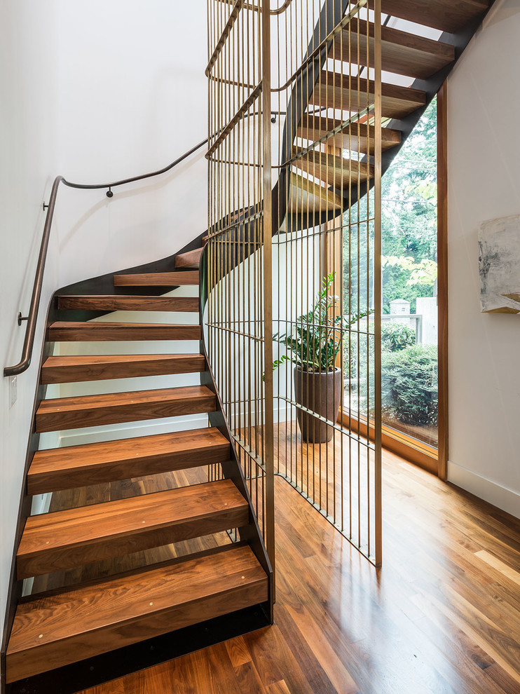 Стильный дизайн: изогнутая лестница в современном стиле с деревянными ступенями и металлическими перилами без подступенок - последний тренд