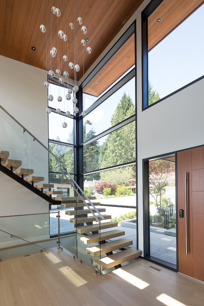 This is an example of a contemporary l-shaped metal railing staircase in Vancouver with glass risers.