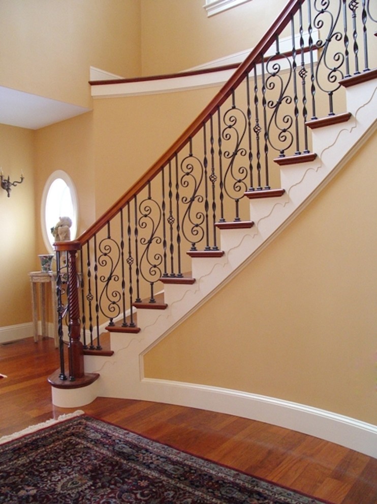 Cette image montre un grand escalier peint courbe design avec des marches en bois et un garde-corps en bois.