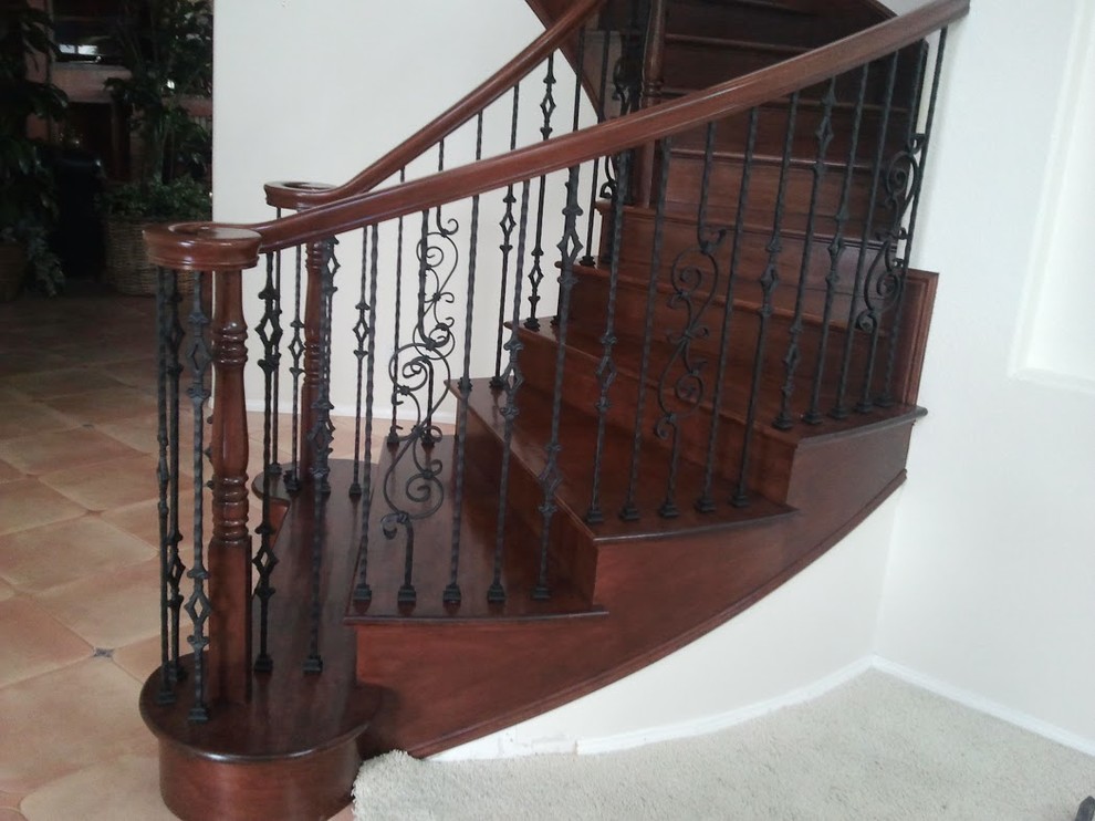 На фото: изогнутая деревянная лестница среднего размера в средиземноморском стиле с деревянными ступенями и деревянными перилами