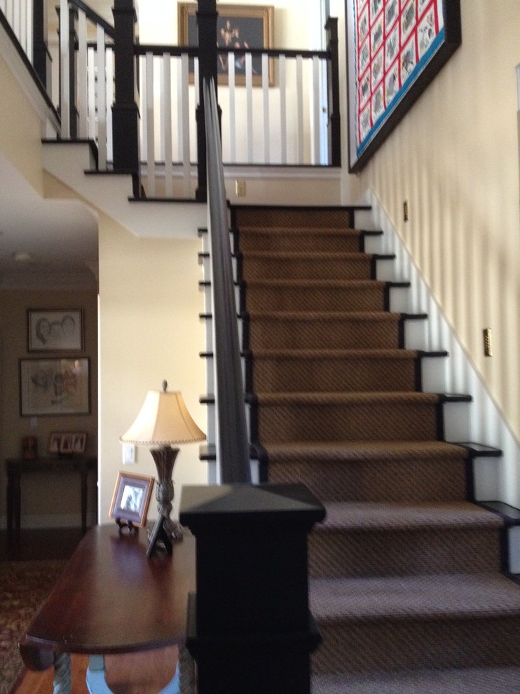 Photo of a medium sized classic carpeted l-shaped wood railing staircase in Other with carpeted risers and feature lighting.