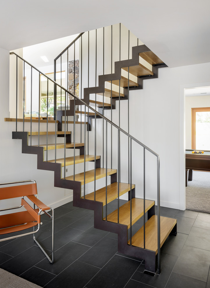На фото: п-образная металлическая лестница среднего размера в стиле модернизм с деревянными ступенями и металлическими перилами с