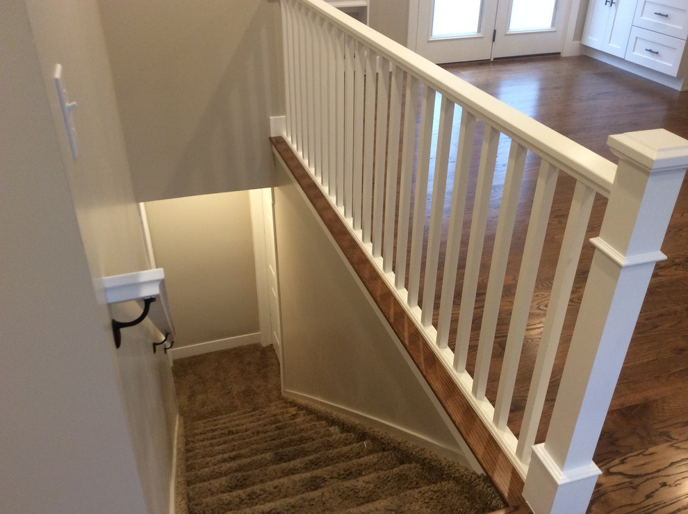 Photo of a medium sized classic carpeted straight wood railing staircase in Salt Lake City with carpeted risers.