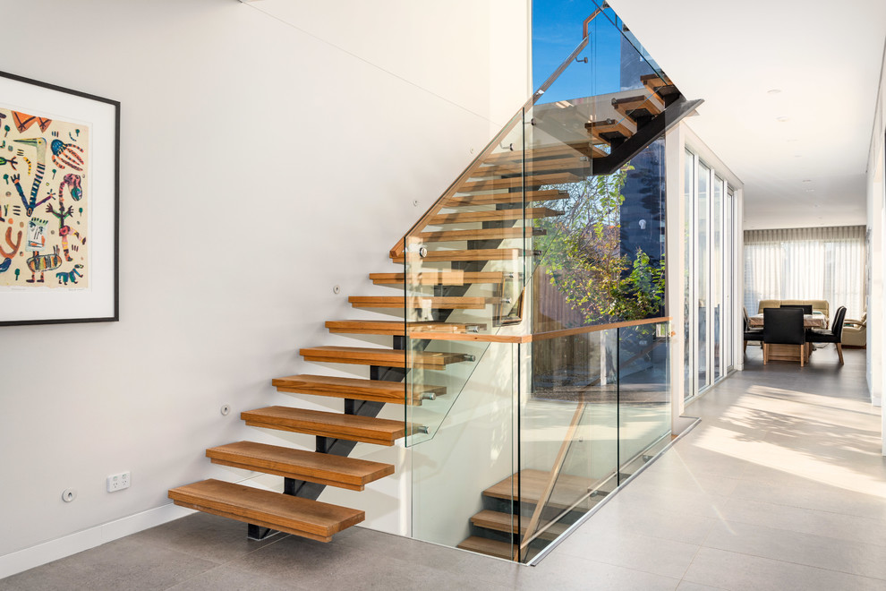 Diseño de escalera en L actual pequeña sin contrahuella con escalones de madera y barandilla de vidrio