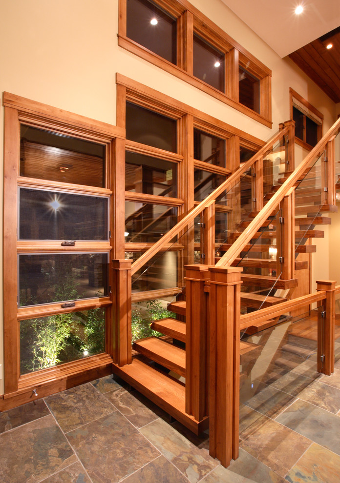 Modelo de escalera recta actual grande con escalones de madera, contrahuellas de vidrio y barandilla de madera