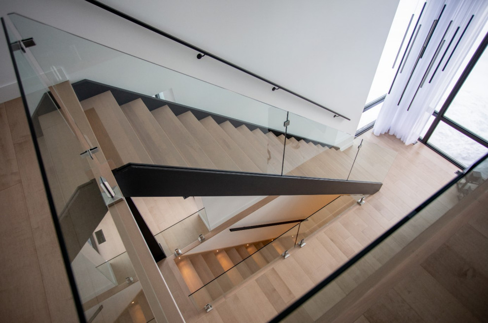 Imagen de escalera de caracol actual con escalones de madera, contrahuellas de madera y barandilla de vidrio