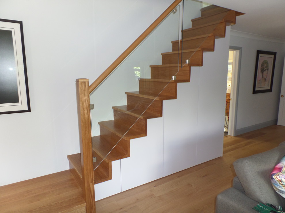 Inspiration pour un escalier droit design de taille moyenne avec des marches en bois, des contremarches en bois et un garde-corps en verre.