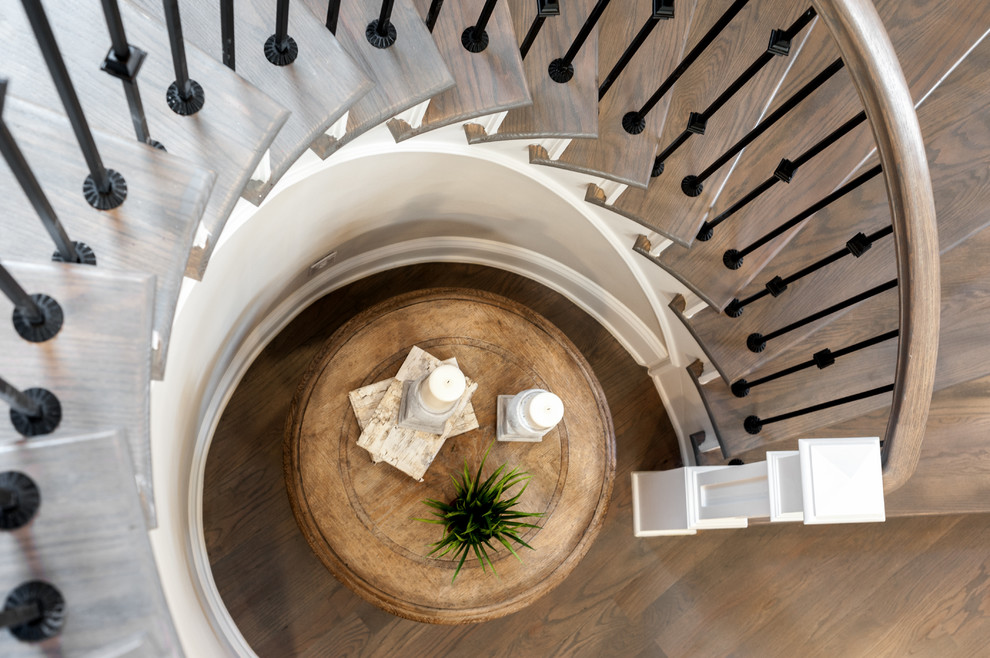 Diseño de escalera curva clásica grande con escalones de madera, contrahuellas de madera pintada y barandilla de metal