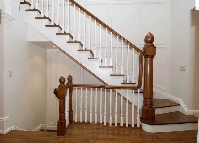 Diseño de escalera en L clásica de tamaño medio con escalones de madera, contrahuellas de madera pintada y barandilla de madera